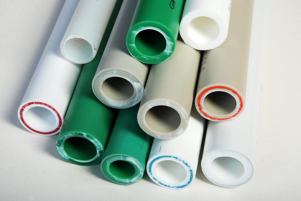 Close-up of stacked plastic pipes next to a propane tank, showing the texture and arrangement of the pipes.