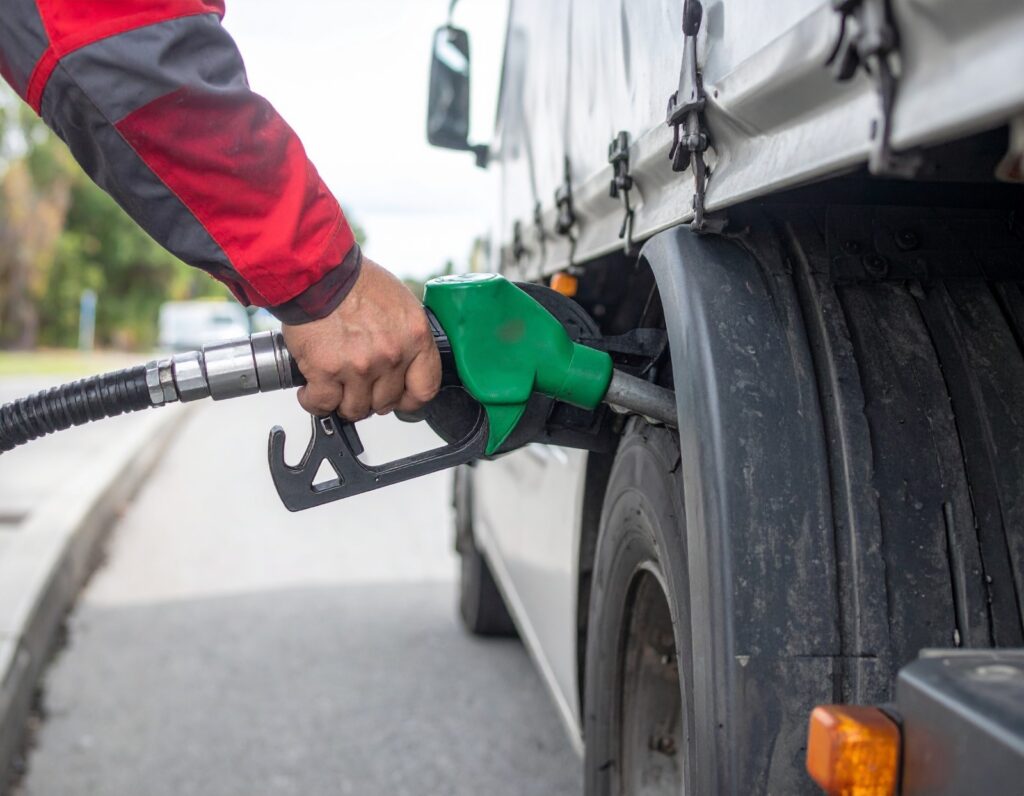 A close-up of a worker’s hand fueling a diesel truck on-site, representing efficient off-road fueling strategies, mobile fuel delivery, and on-site equipment diesel service.