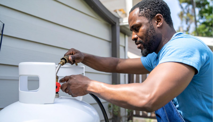 A propane technician filling a large residential propane tank, illustrating propane usage and the essential role of propane service providers in fuel delivery.