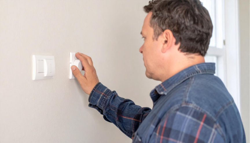 A homeowner turning up the thermostat in a warm home, highlighting propane usage and how propane service providers help manage winter propane costs effectively.