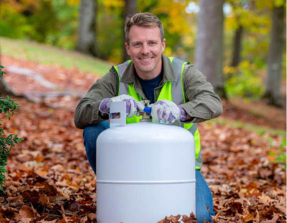 A worker performing a safety inspection on a propane tank using PPE, following a winter propane checklist and propane safety tips to ensure safe operation.