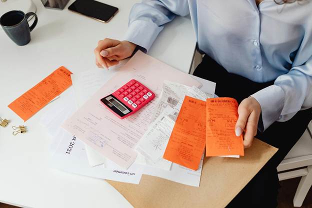 Business owner using a calculator to review receipts and identify ways to reduce winter energy costs.