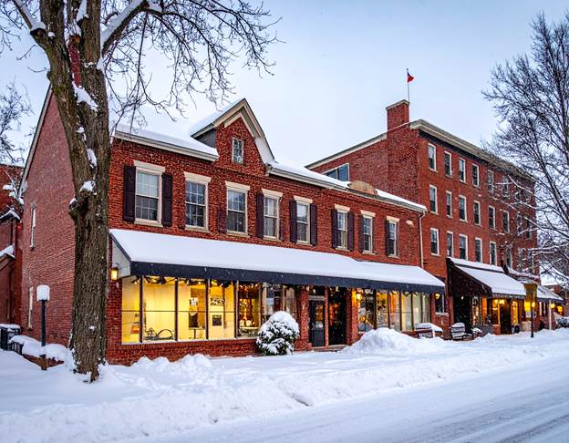 A storefront in winter brightly lit and heated safely using Central Penn Propane. Snow surrounds the building, highlighting its cozy ambiance.