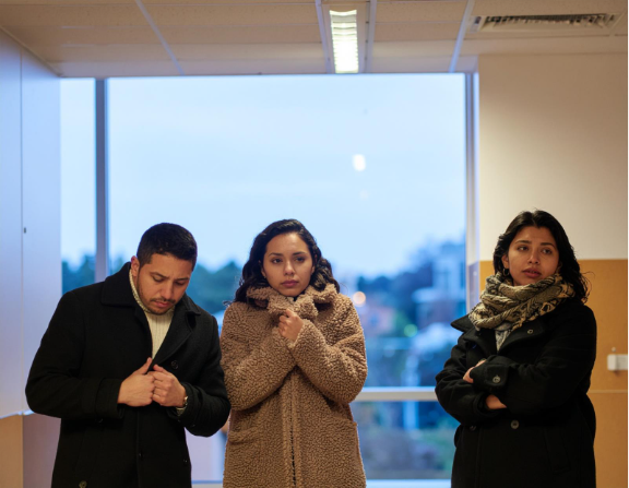 Three employees wearing coats inside a commercial building trying to stay warm, illustrating the comfort and efficiency provided by propane heating.